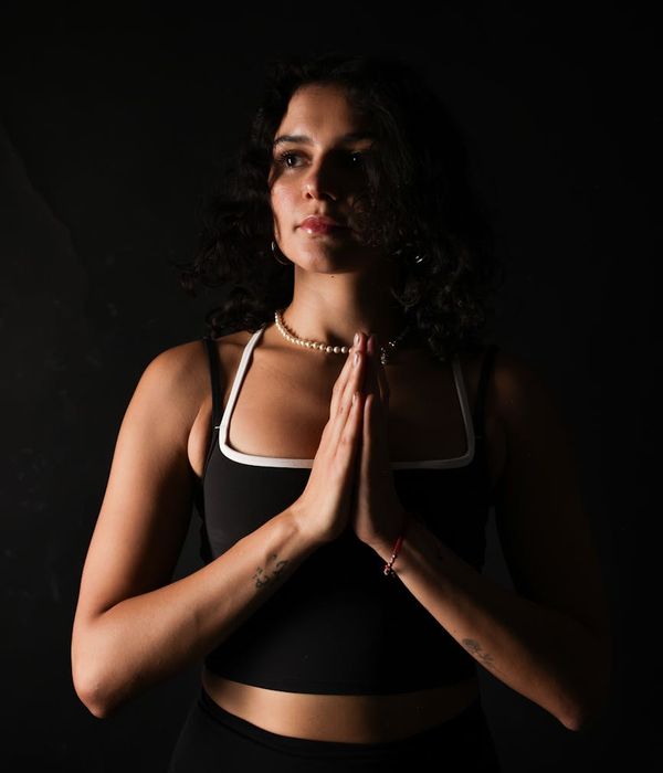 Woman performing a gentle stretching pose in a calm, dark environment.